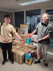 Dwóch uczniów prezentuje paczki zebrane w szkole